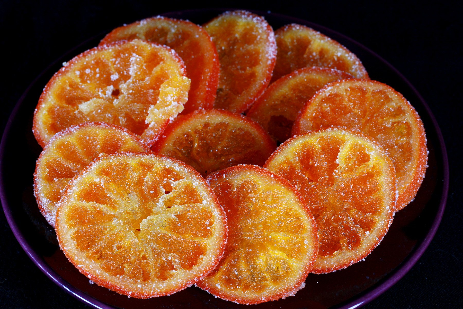 A small blue plate with slices of candied oranges spread out on it.