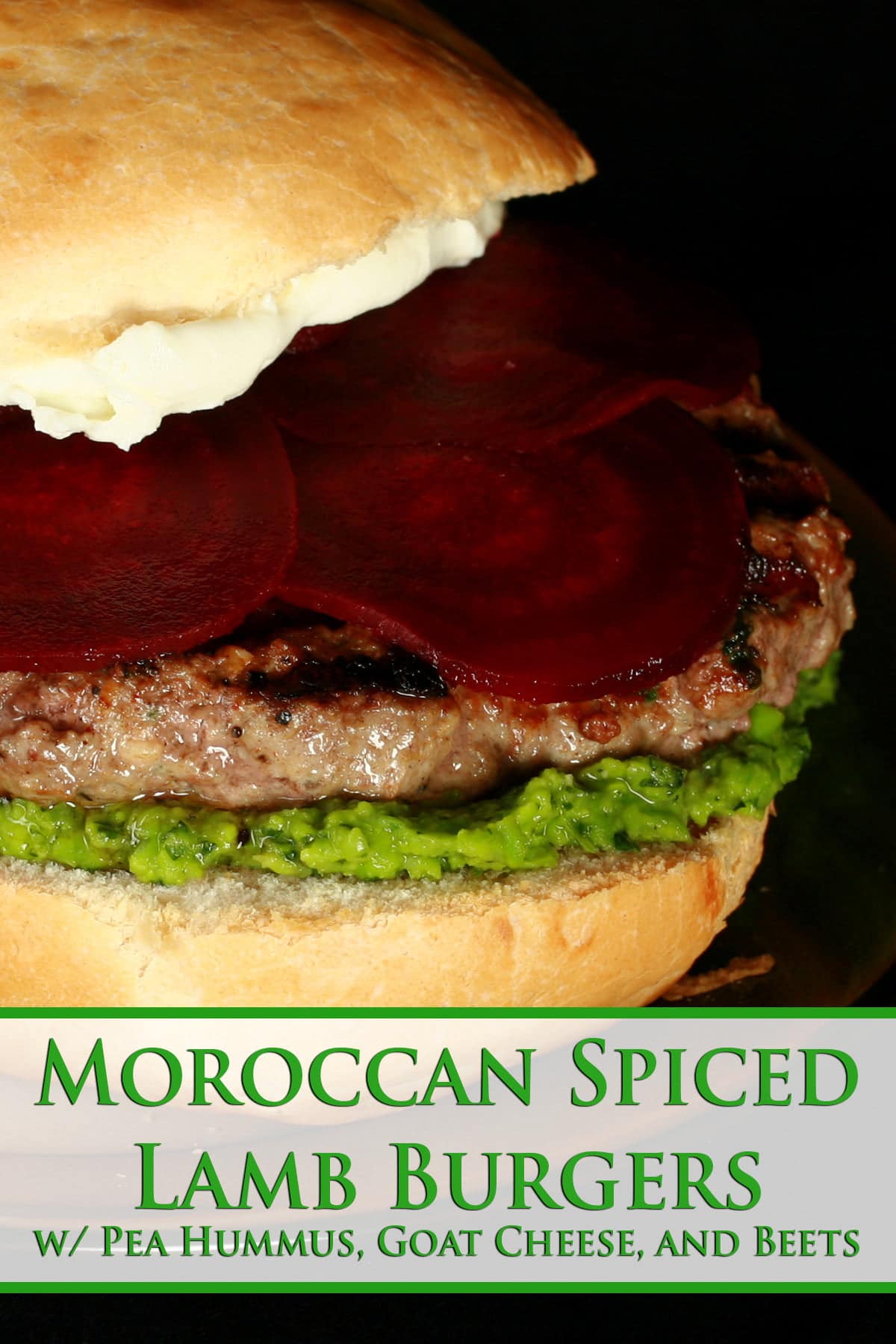 Close up view of a burger with a green spread, a goat cheese spread, and beet slices on it.