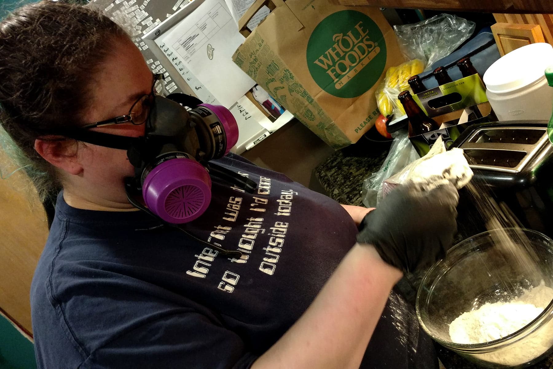 The author is pictured wearing a dark blue shirt and a half mask. She is wearing black nitrile gloves while handling vital wheat gluten.