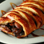 A braided puff pastry shows a mushroom filling and a balsamic vinegar drizzle over it.