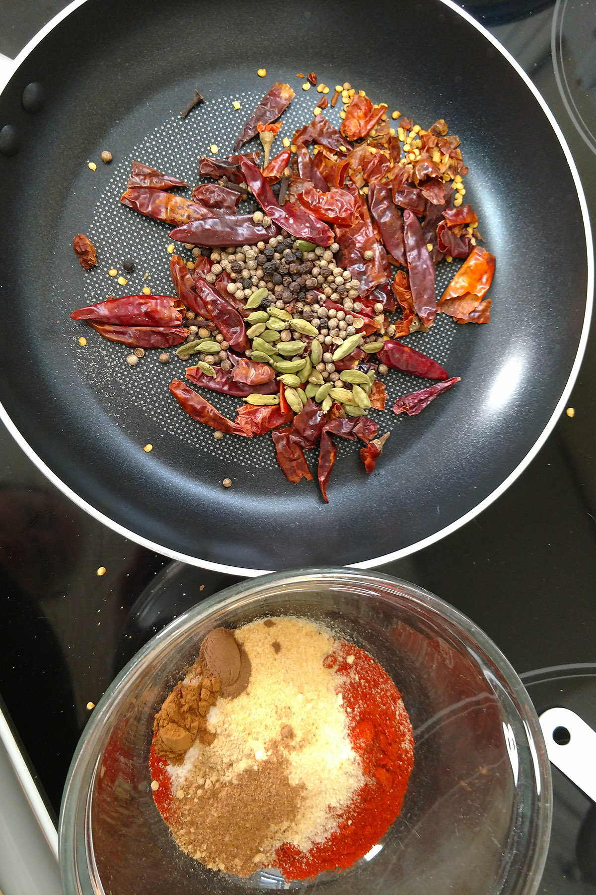 Dried chilies and other spices in a frying pan.