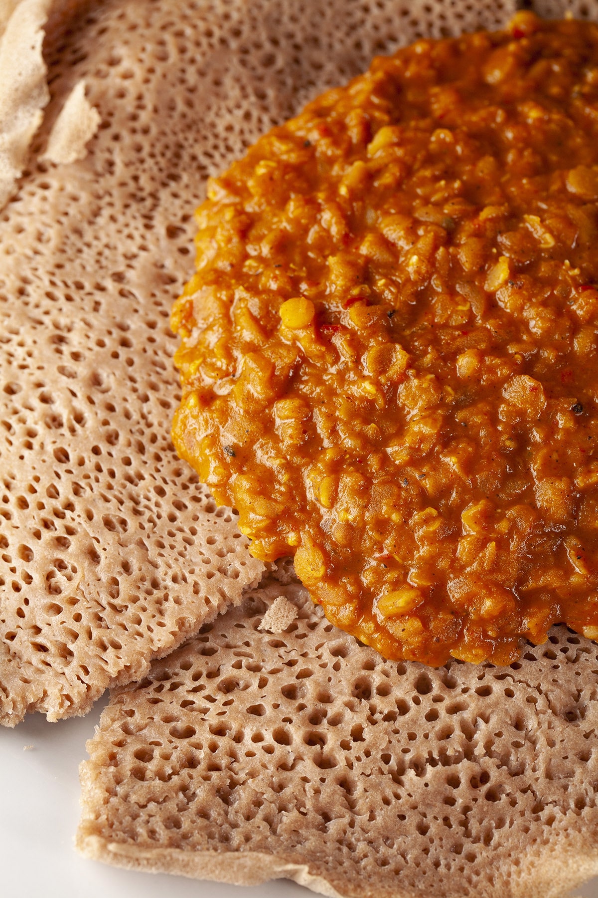 A generous portion of berbere lentils, on a pile of injera bread.