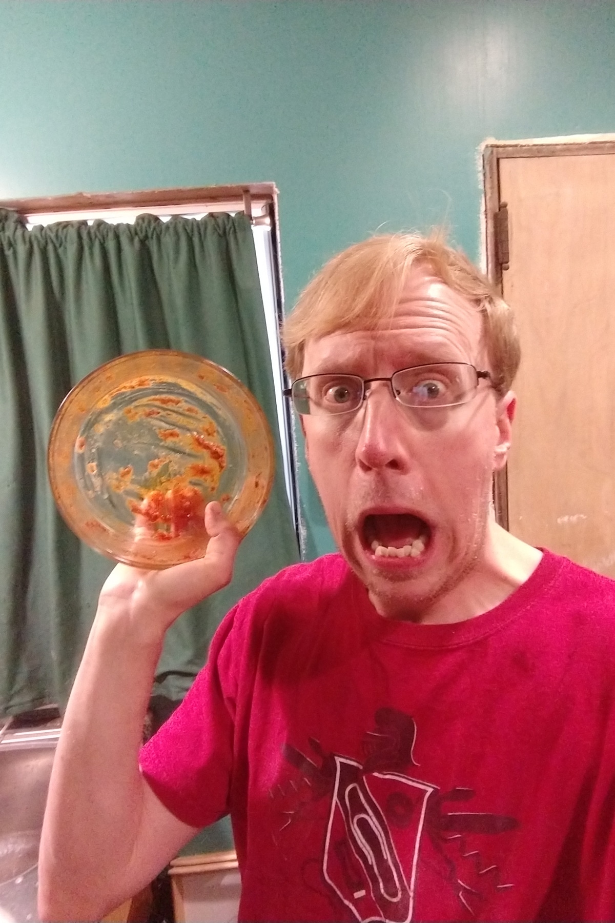 A blonde man holds up an empty bowl, with a horrified look on his face.