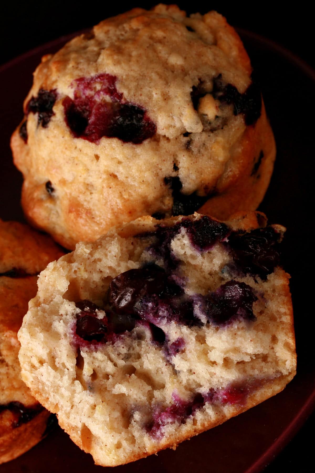 A small purple plate holds two and a half apple blueberry muffins.