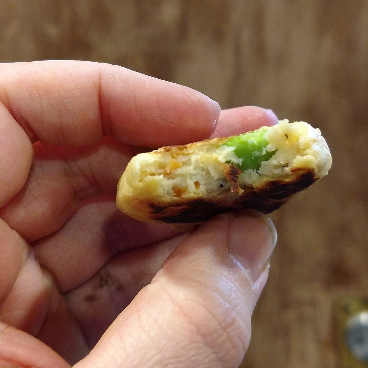 A hand holds an edamame tofu nugget.