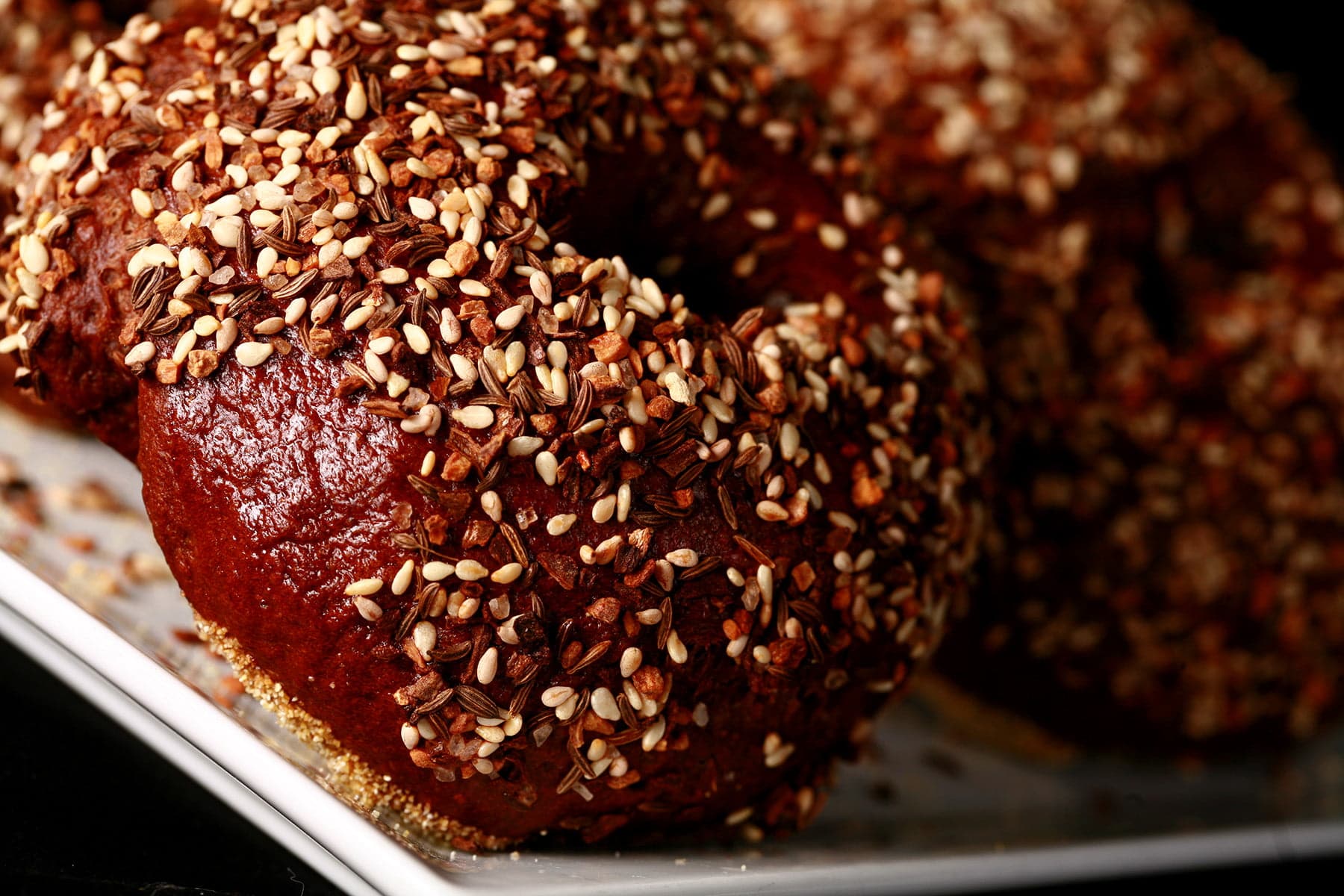 A very close up view of an "everything" style Pumpernickel Bagel.