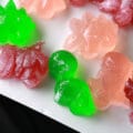 A white plate with homemade BCAA Gummies. They are pink, green, and purple, shaped like dinosaurs.