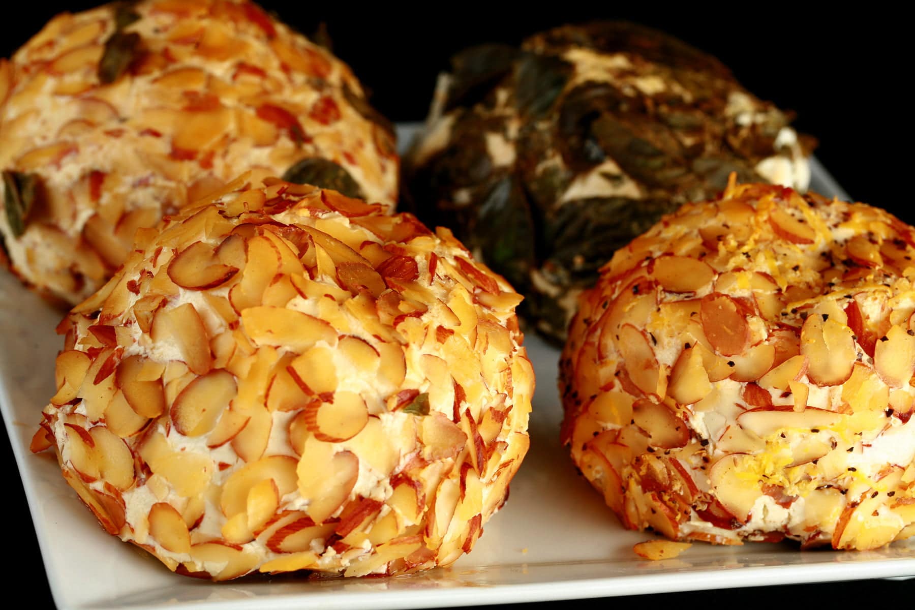 4 smoked cheese balls - with various coatings - are arranged on a plate.