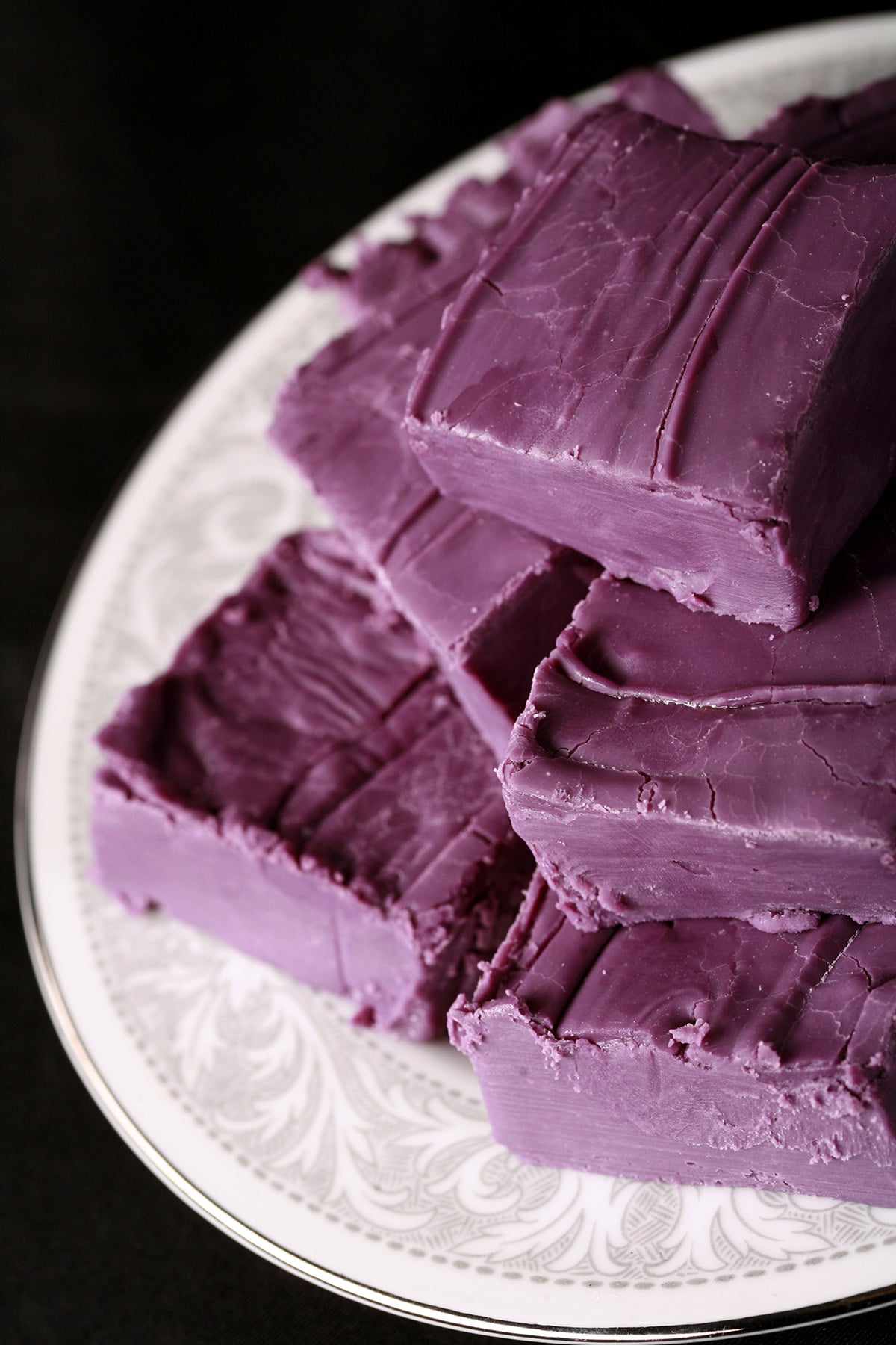 A small white plate stacked with squares of deep purple ube white chocolate fudge.