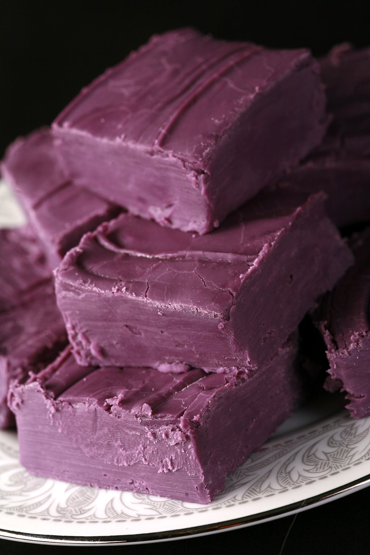 A small white plate stacked with squares of deep purple fudge.