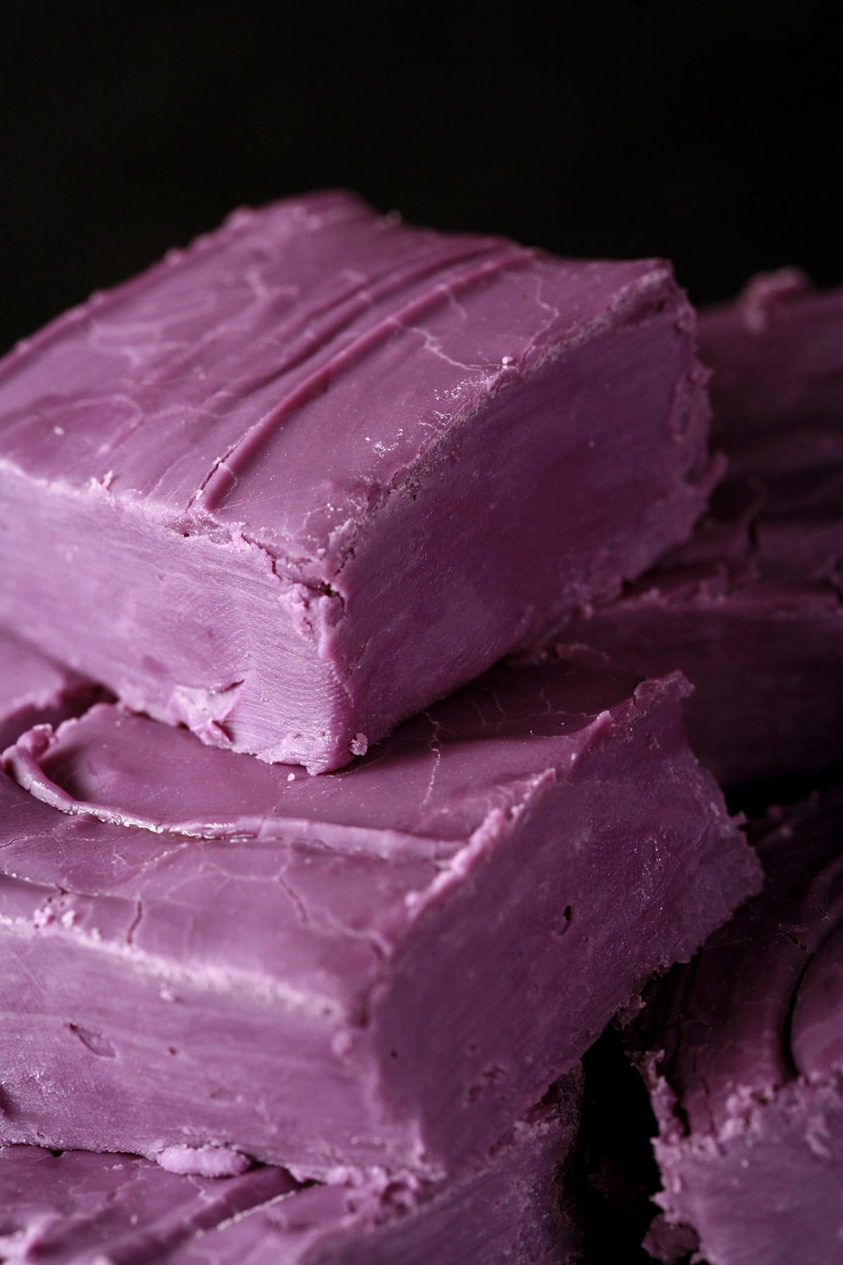 A small white plate stacked with squares of deep purple fudge.