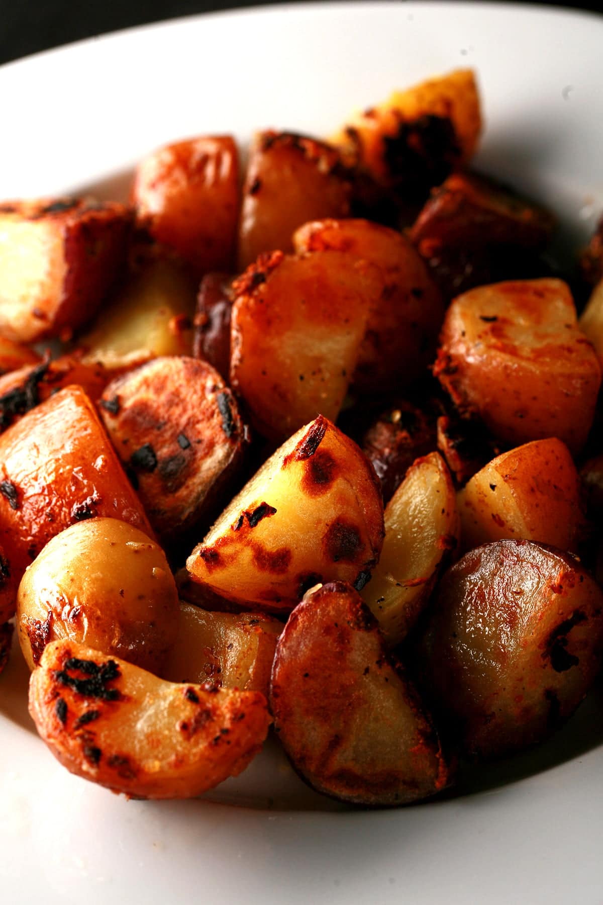 A white plate with a large helping of the BEST breakfast potatoes ever - chunks of red potatoes with charring and blistering on the surfaces.