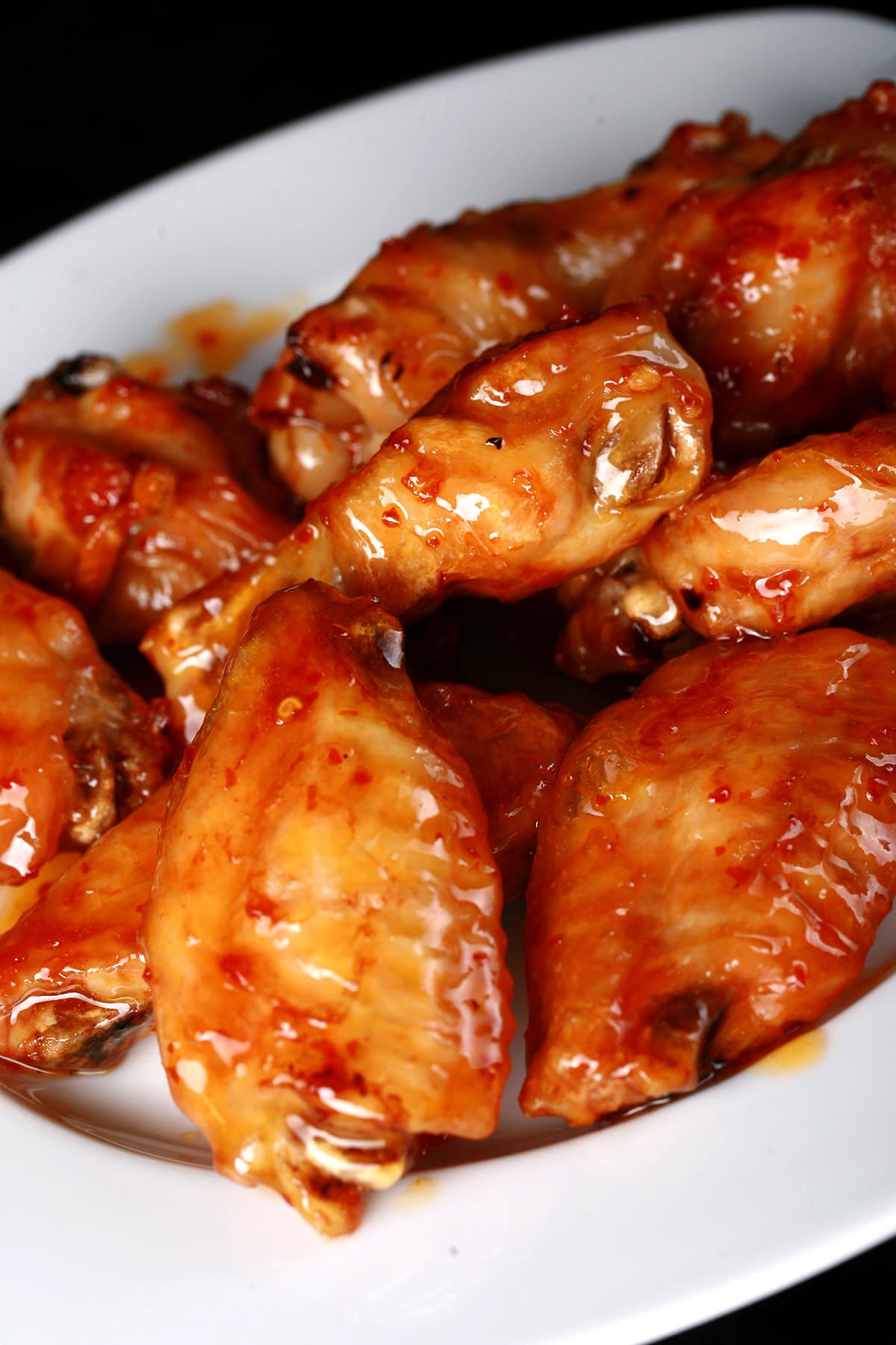 A large white plate piled with fried wings in a reddish glaze.