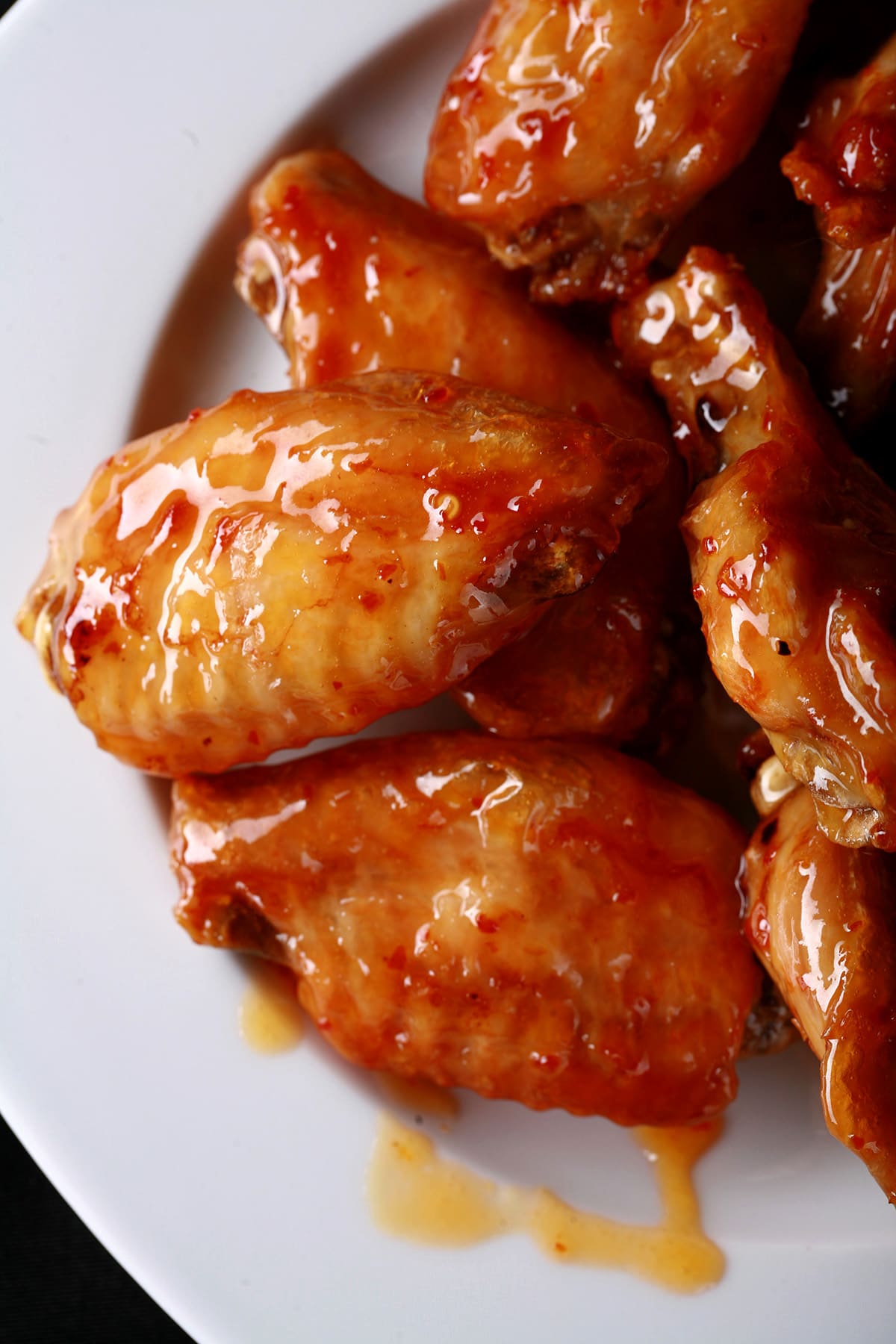 A large white plate piled with fried honey jeow glazed wings - a reddish sauce.
