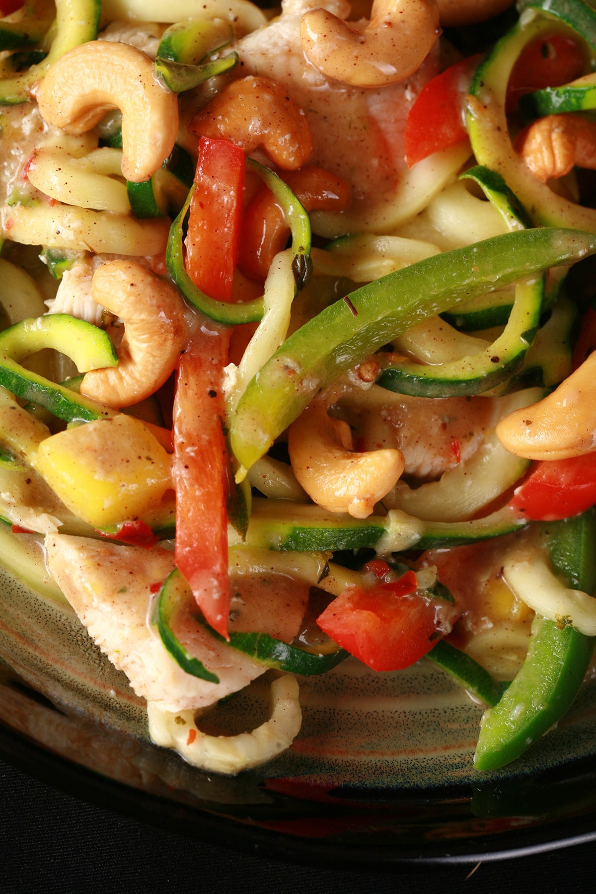 A plate of tropical chicken zoodles. Spiralized zucchini, pineapples, red pepper, cashews, and more.