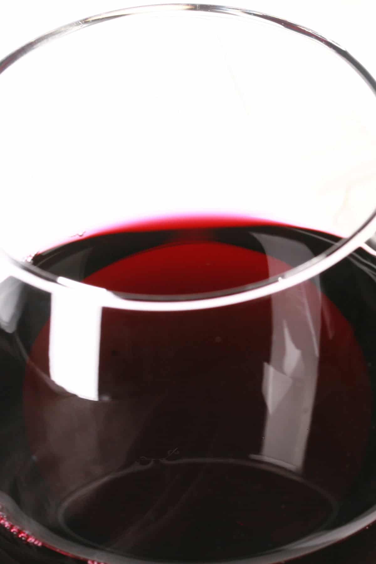 A very close up view of a dark purple wine, in a glass.