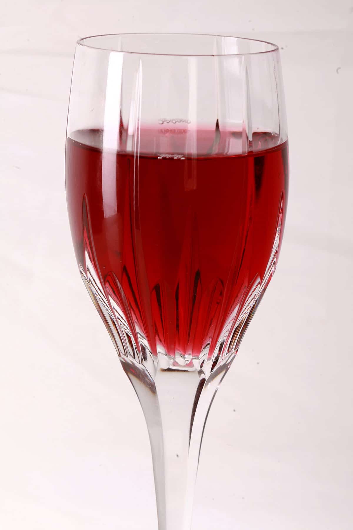 A faceted wine glass full of blueberry mead.