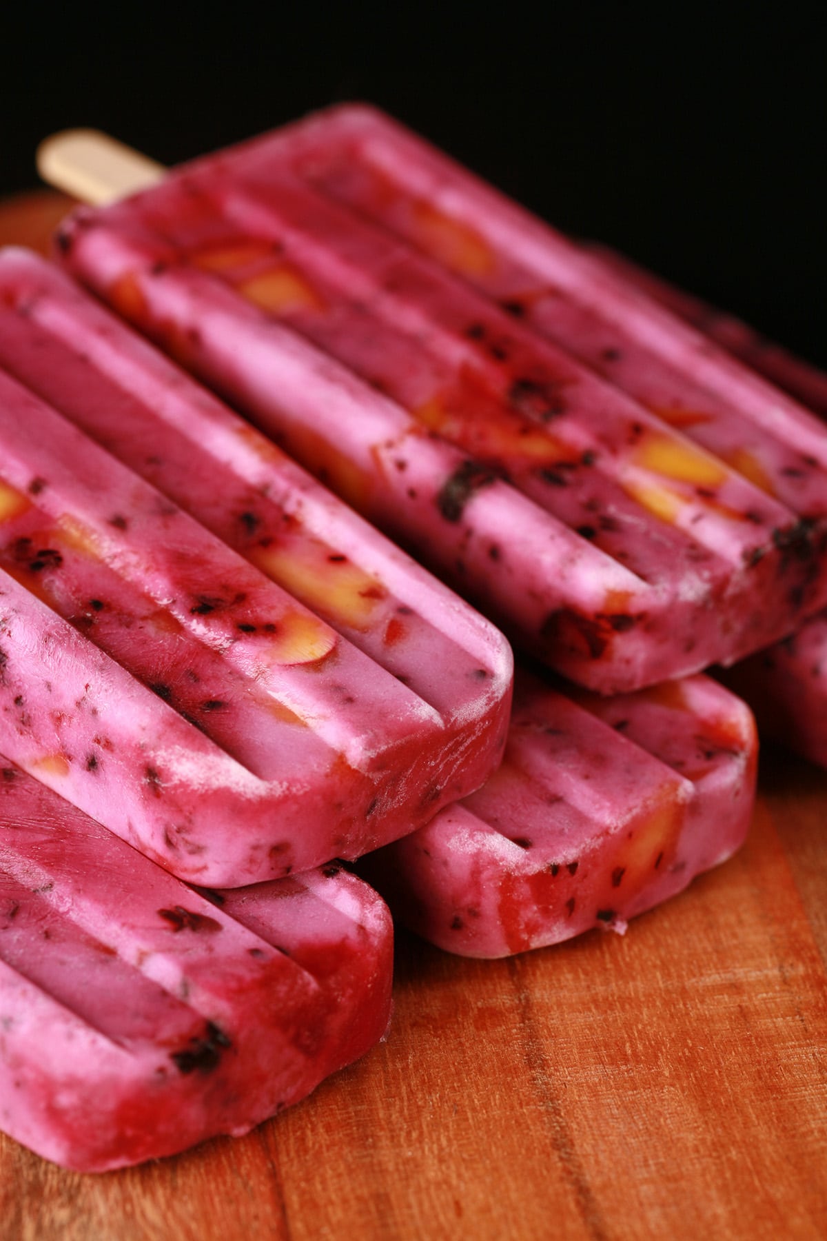 Close up image of light purple popsicles with chunks of blackberries and peaches in them - Blackberry Peach Pops