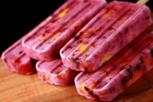 Close up image of light purple popsicles with chunks of blackberries and peaches in them - Blackberry Peach Pops