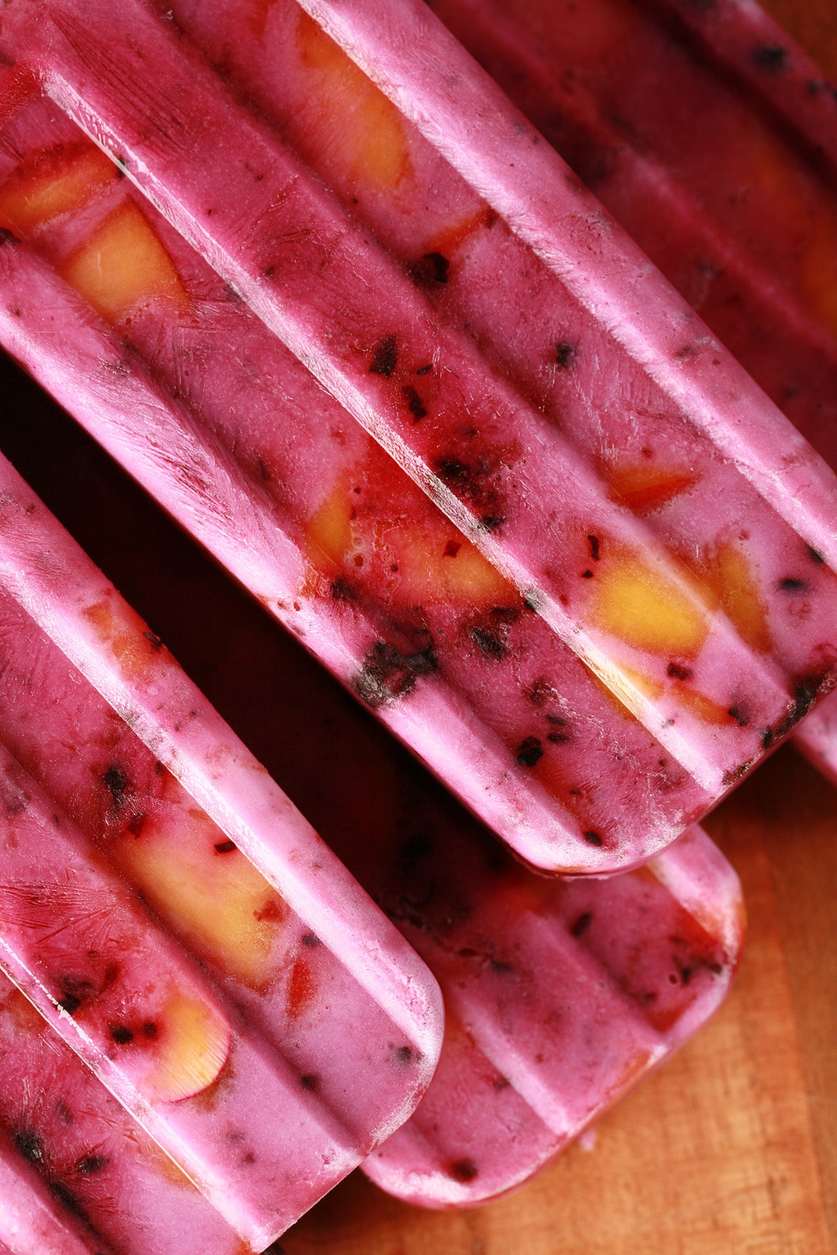 Close up image of light purple popsicles with chunks of blackberries and peaches in them - Blackberry Peach Pops