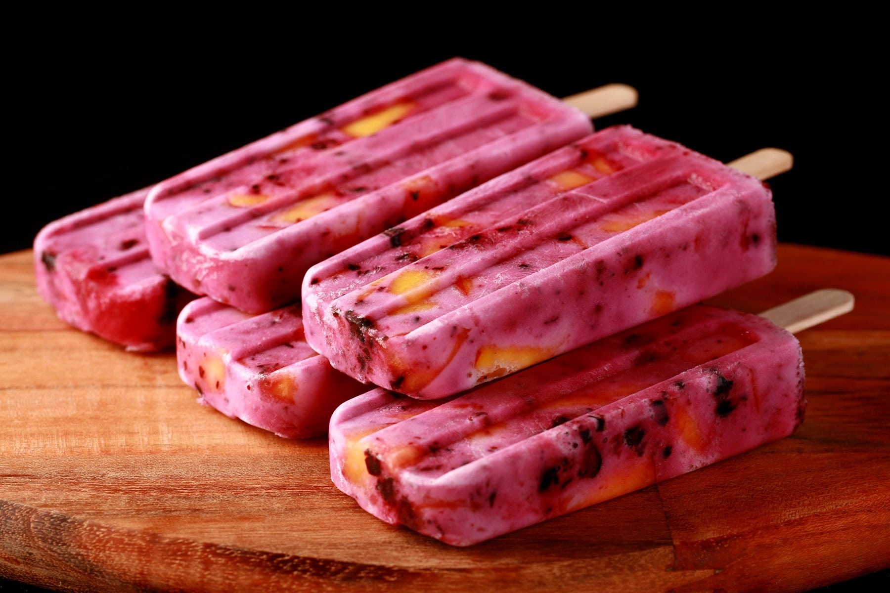 Close up image of light purple popsicles with chunks of blackberries and peaches in them - Blackberry Peach Pops