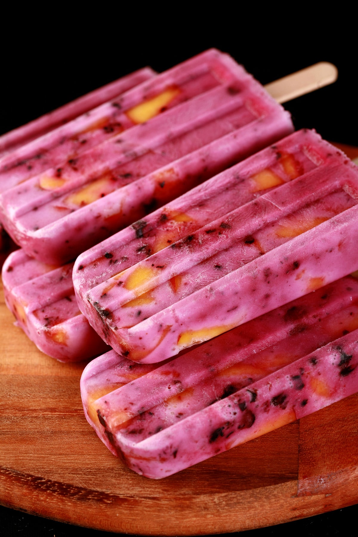 Close up image of light purple popsicles with chunks of blackberries and peaches in them - Blackberry Peach Pops