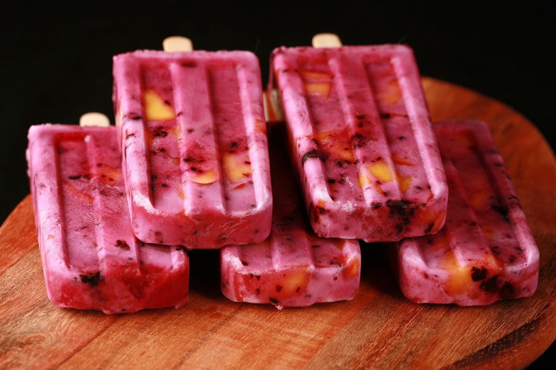 Close up image of light purple popsicles with chunks of blackberries and peaches in them - Blackberry Peach Pops