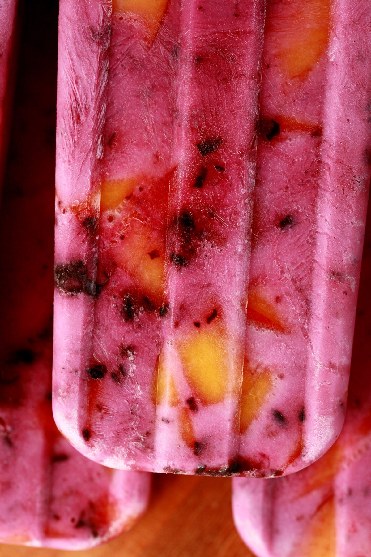 Close up image of light purple popsicles with chunks of blackberries and peaches in them - Blackberry Peach Pops