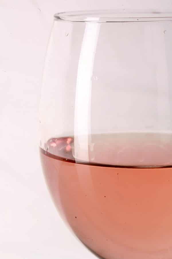 Close up photo of a single glass of pale pink wine