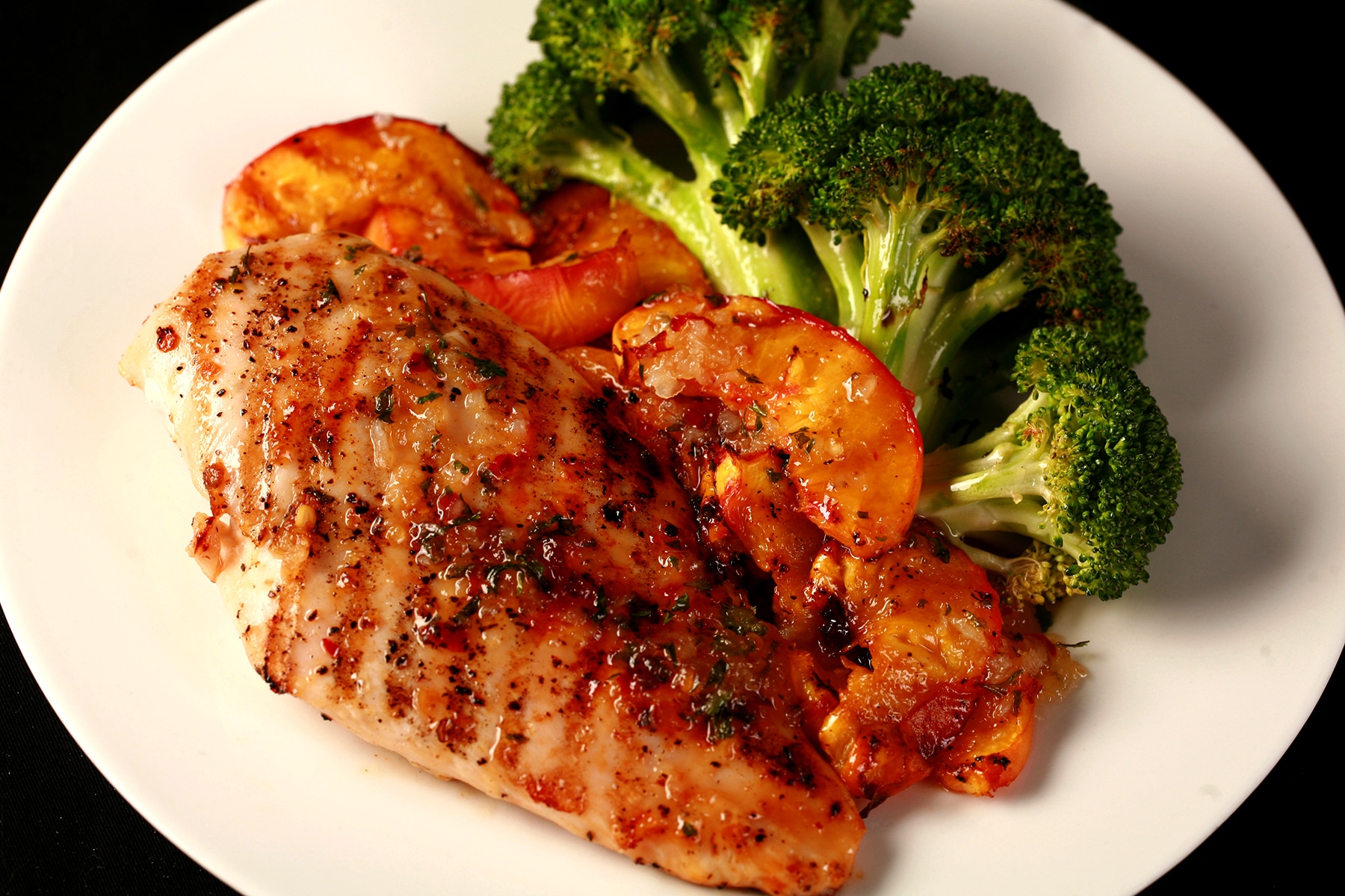 Image of a plate of food: 1 grilled Southern Comfort glazed chicken breast - visibly seasoned - grilled peach slices, and broccoli