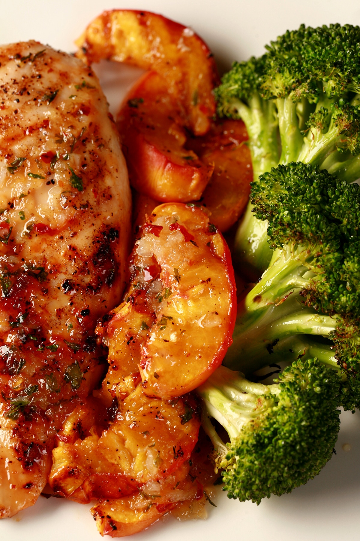 Image of a plate of food: 1 grilled chicken breast - visibly seasoned - grilled peach slices, and broccoli