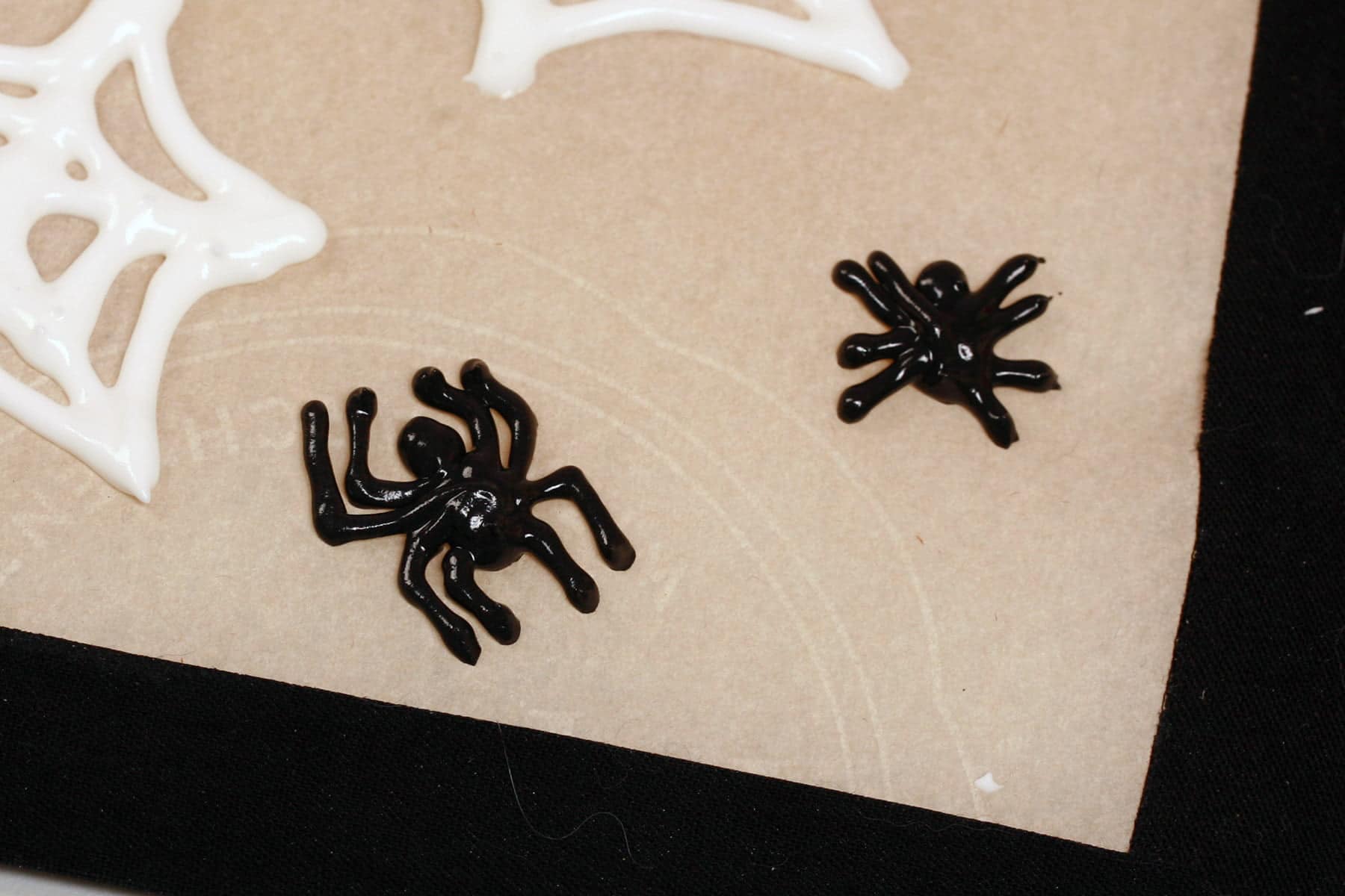 a close up view of two shiny black spiders, piped out of royal icing.