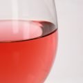 A glass of pale red strawberry wine.