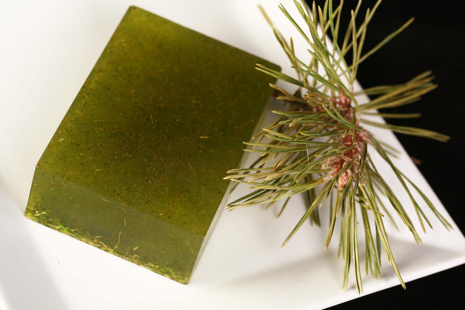 A green bar of soap, with green flecks of pine needles throughout.