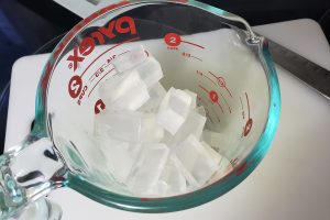 A glass measuring cup with cubes of clear soap in it.