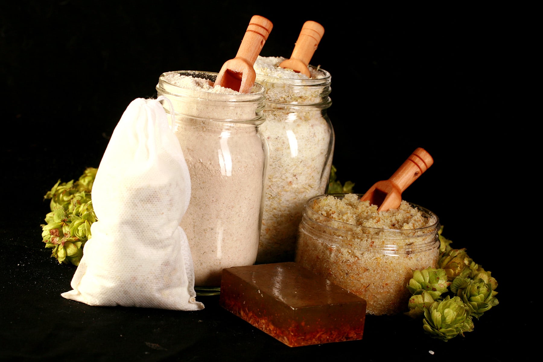 A 4 piece hop spa set, including a bar of hop soap, a canister of hop salt scrub, a jar of hop bath salt, and a jar of hop malted milk bath.