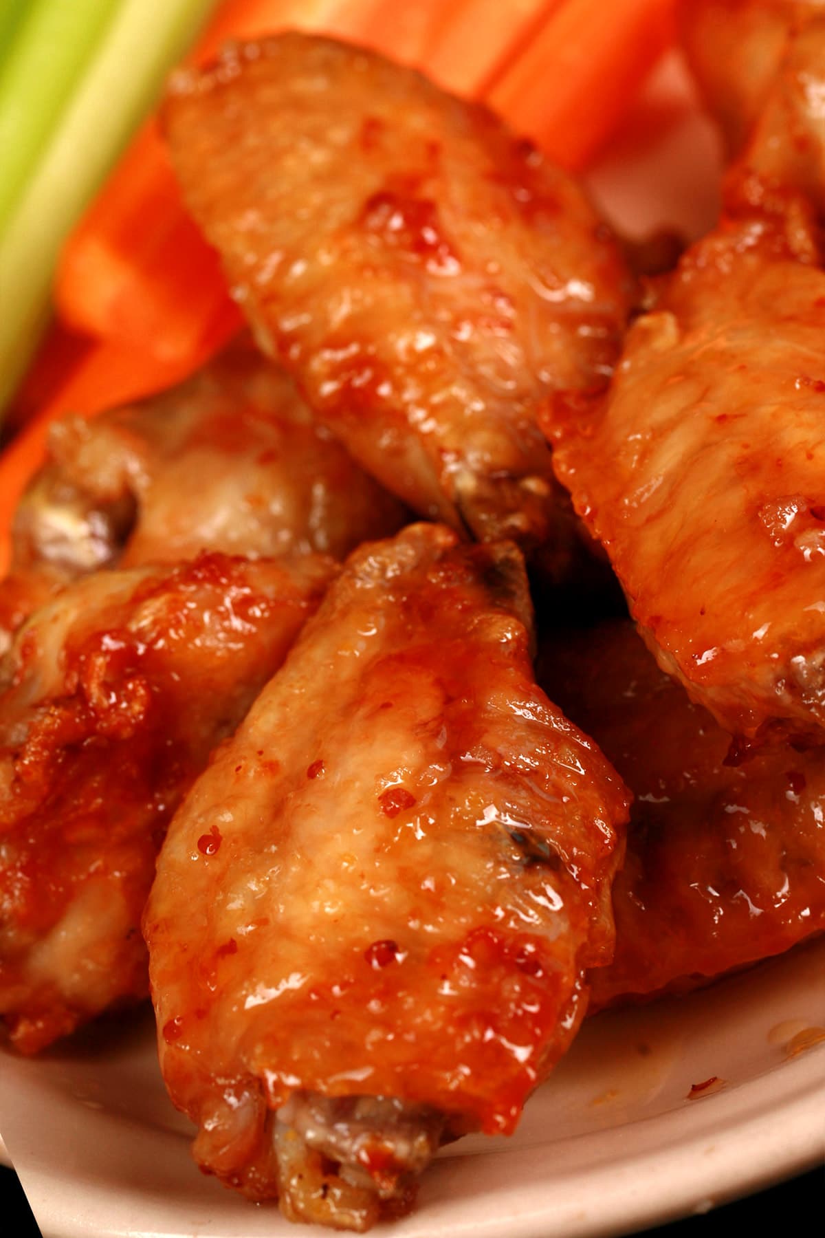A small plate of maple dijon wings, with carrot and celery sticks on the side.