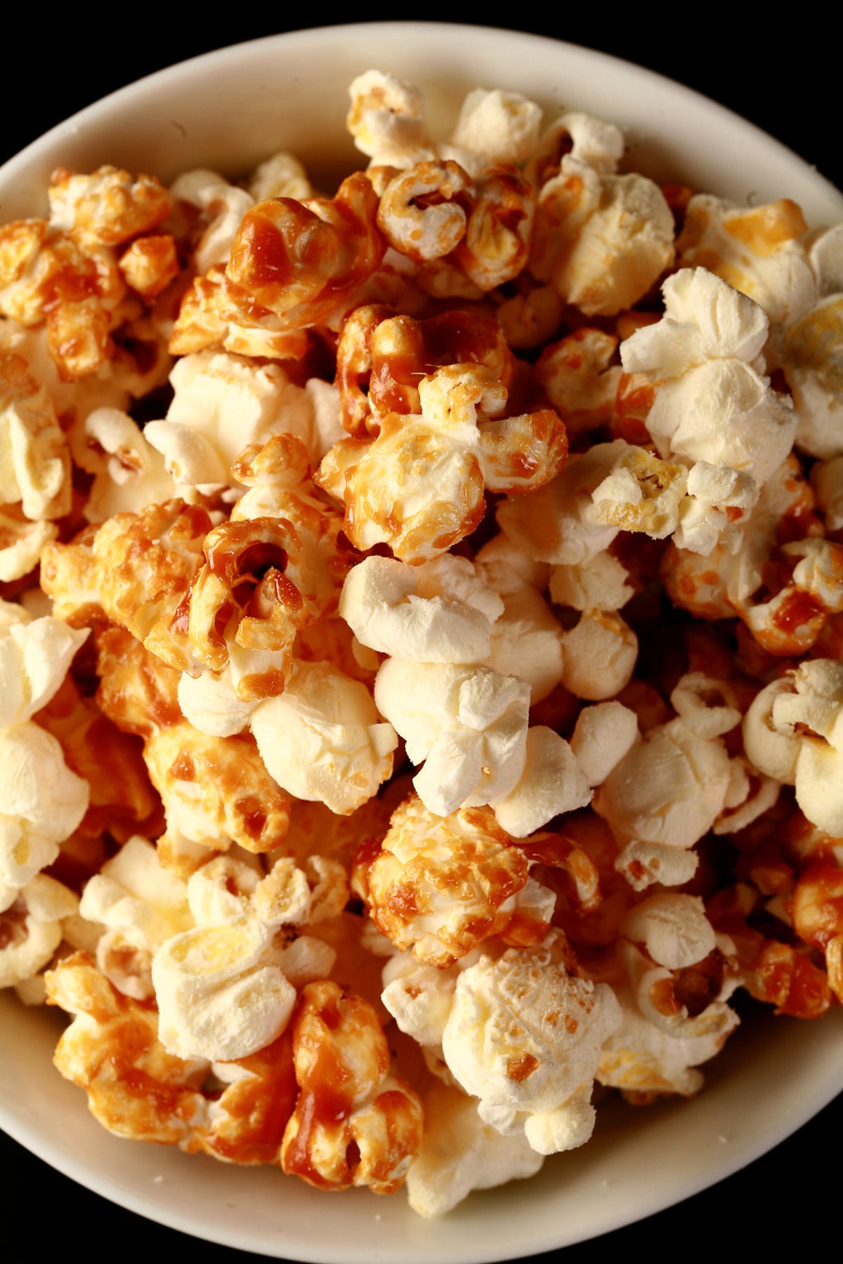 Close up photo of a bowl of two-tone popcorn: Maple White Cheddar Popcorn. Half of the popcorn is covered with maple caramel, the other half is white - white cheddar.