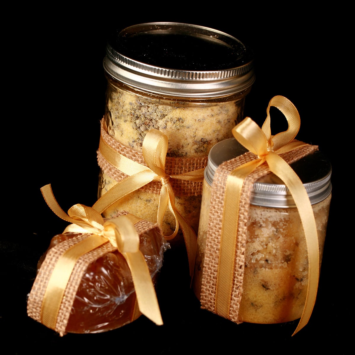 A 3 piece mustard bath gift set - the mustard bath salt, a salt scrub, and a nubby yellow mustard soap. They are all accented with yellow ribbon.