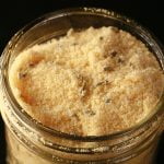Close up view of a mason jar filled with yellow bath salts. It has purple flecks throughout. This is Mustard Bath.