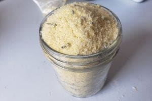 Close up view of a mason jar filled with yellow bath salts. It has purple flecks throughout.