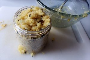 Close up view of a small jar filled will a wet, yellow sandy looking mixture.