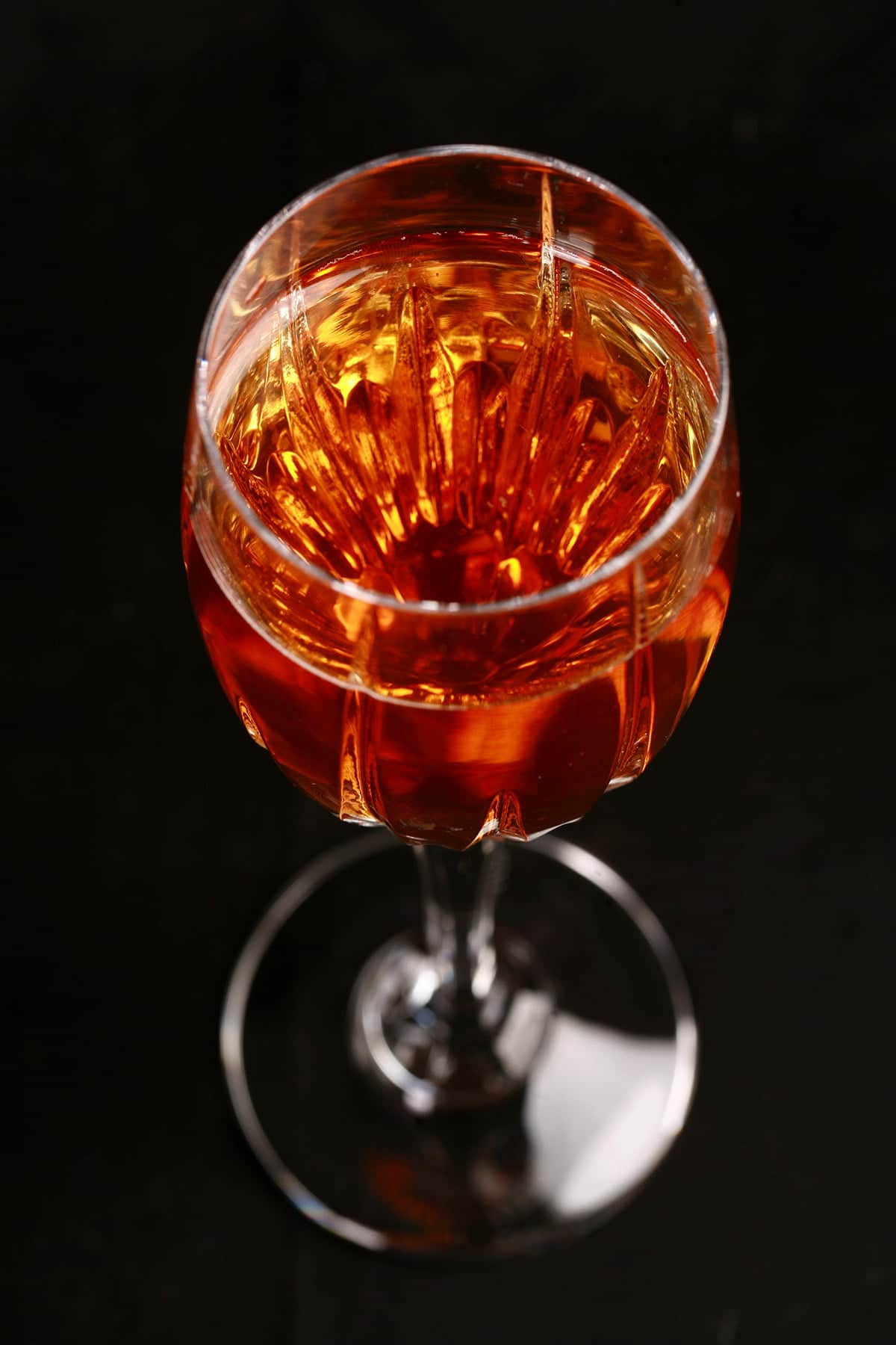 Close up photo of a tall wine glass with dark amber mead in it.
