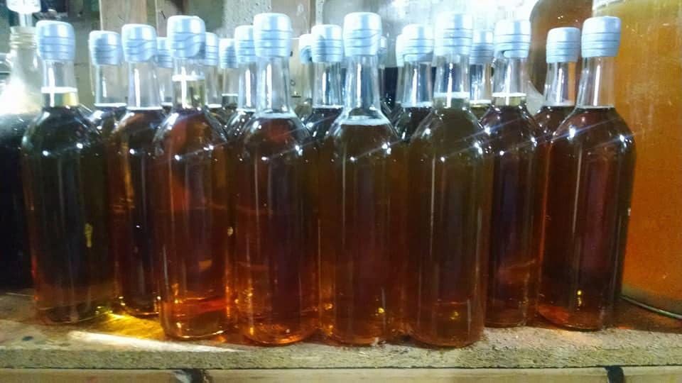 Row of wine bottles filled with deep amber coloured mead.