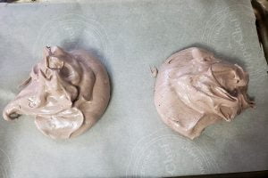 Two mounds of raw chocolate meringue on a baking sheet lined with parchment paper.