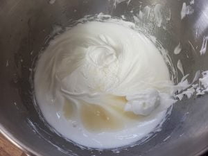 A bowl of meringue, with vanilla extract, corn starch, and vinegar visible.