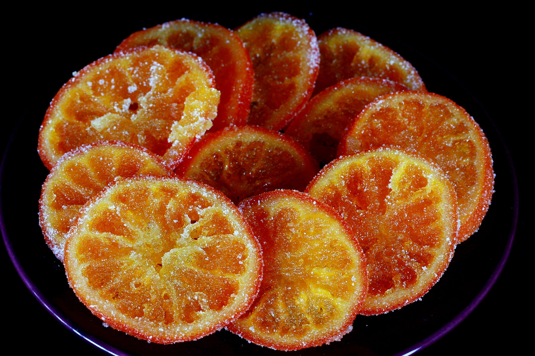 A blue plate with candied oranges arranged on it.