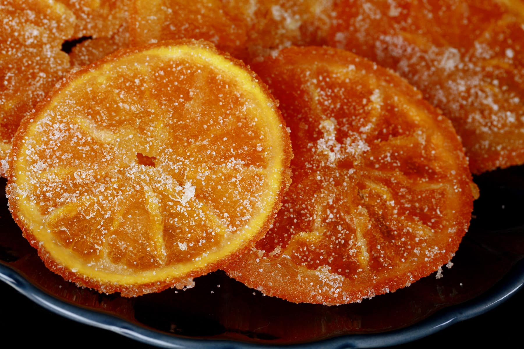 A blue plate with candied orange slices arranged on it.