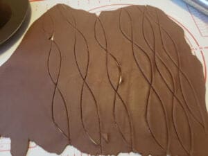 A rolled out piece of chocolate fondant, with leaf shapes cut from it.