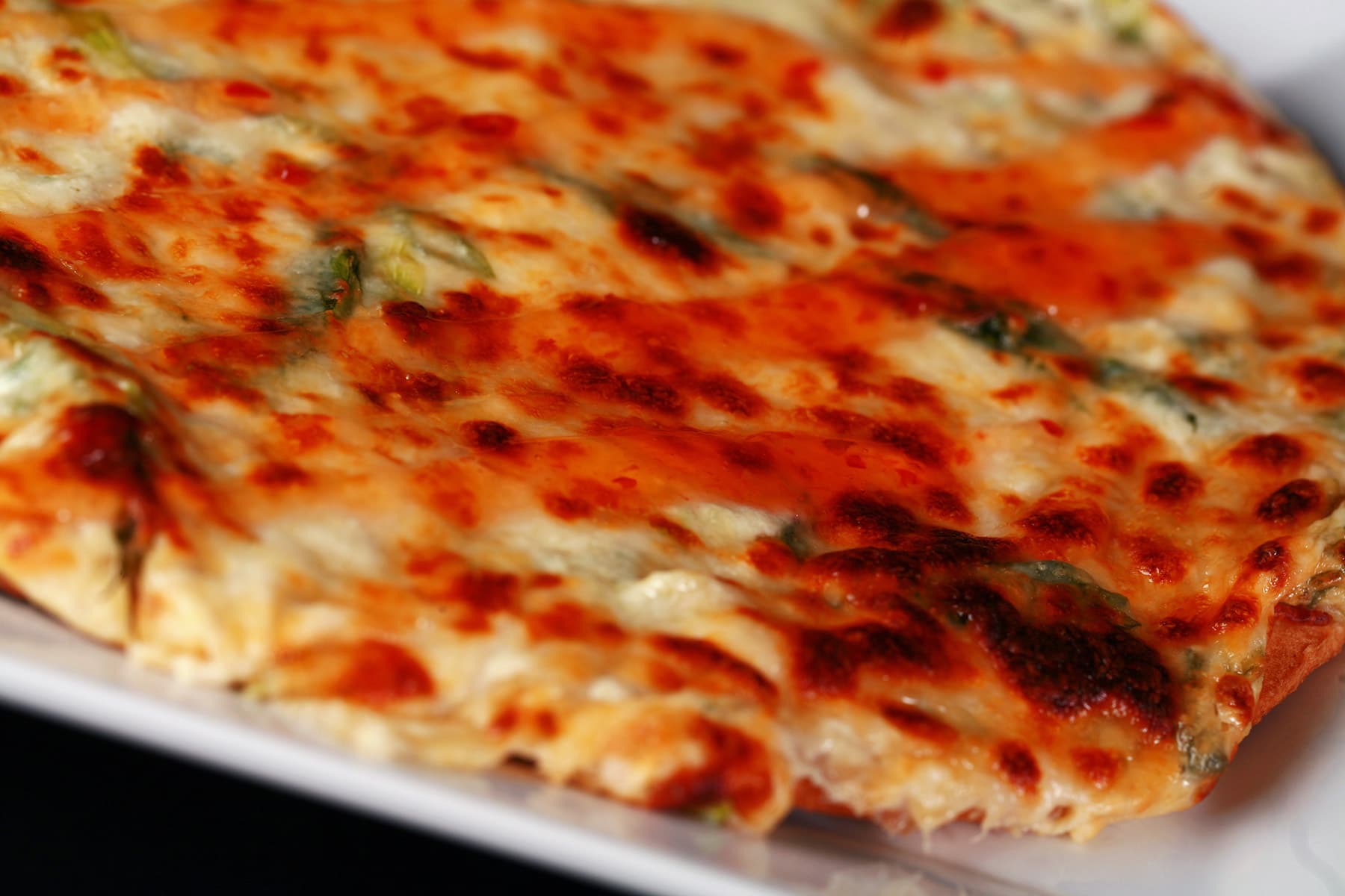 A close up view of a whole crab rangoon pizza, thin crust.